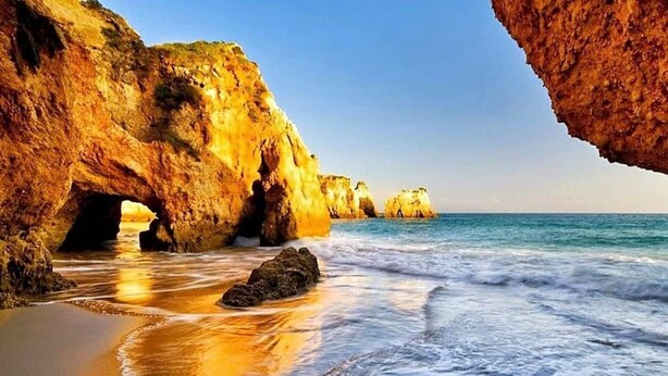 Una playa con formaciones rocosas y olas.