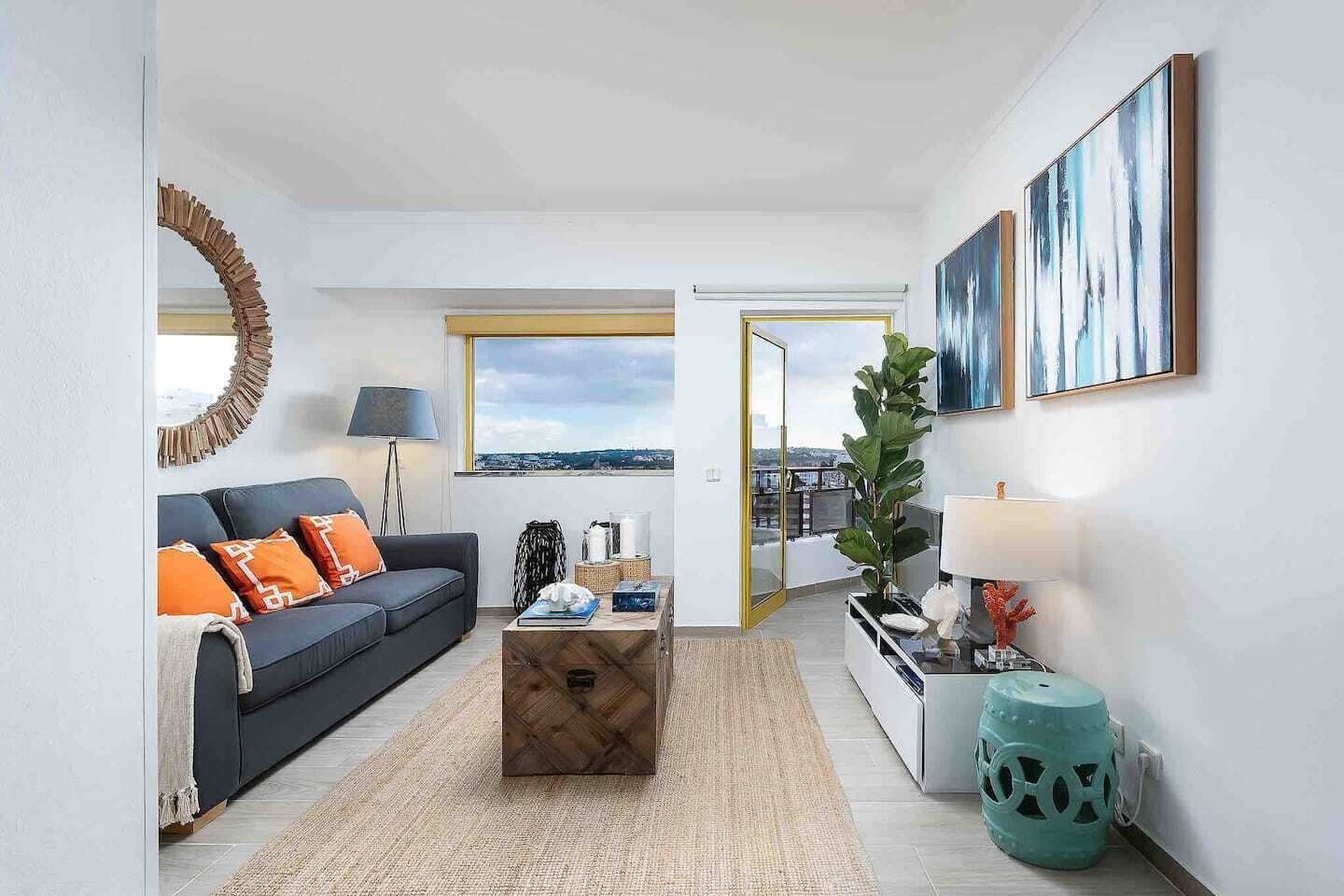 Una sala de estar moderna con un sofá, una mesa de centro y vistas de la ciudad a través de un ventanal.