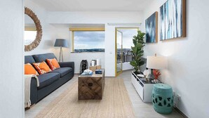 Una sala de estar moderna con un sofá, una mesa de centro y vistas de la ciudad a través de un ventanal.