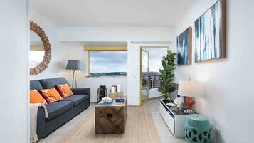 Una sala de estar moderna con un sofá, una mesa de centro y vistas de la ciudad a través de un ventanal.