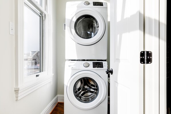 Une machine à laver et un sèche-linge superposés dans une pièce avec une fenêtre.