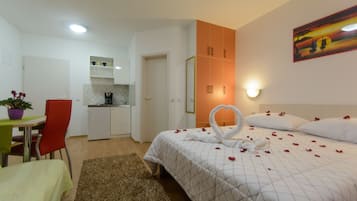 Una camera d'albergo con un letto, una scrivania, una sedia, un angolo cottura e un quadro appeso al muro.