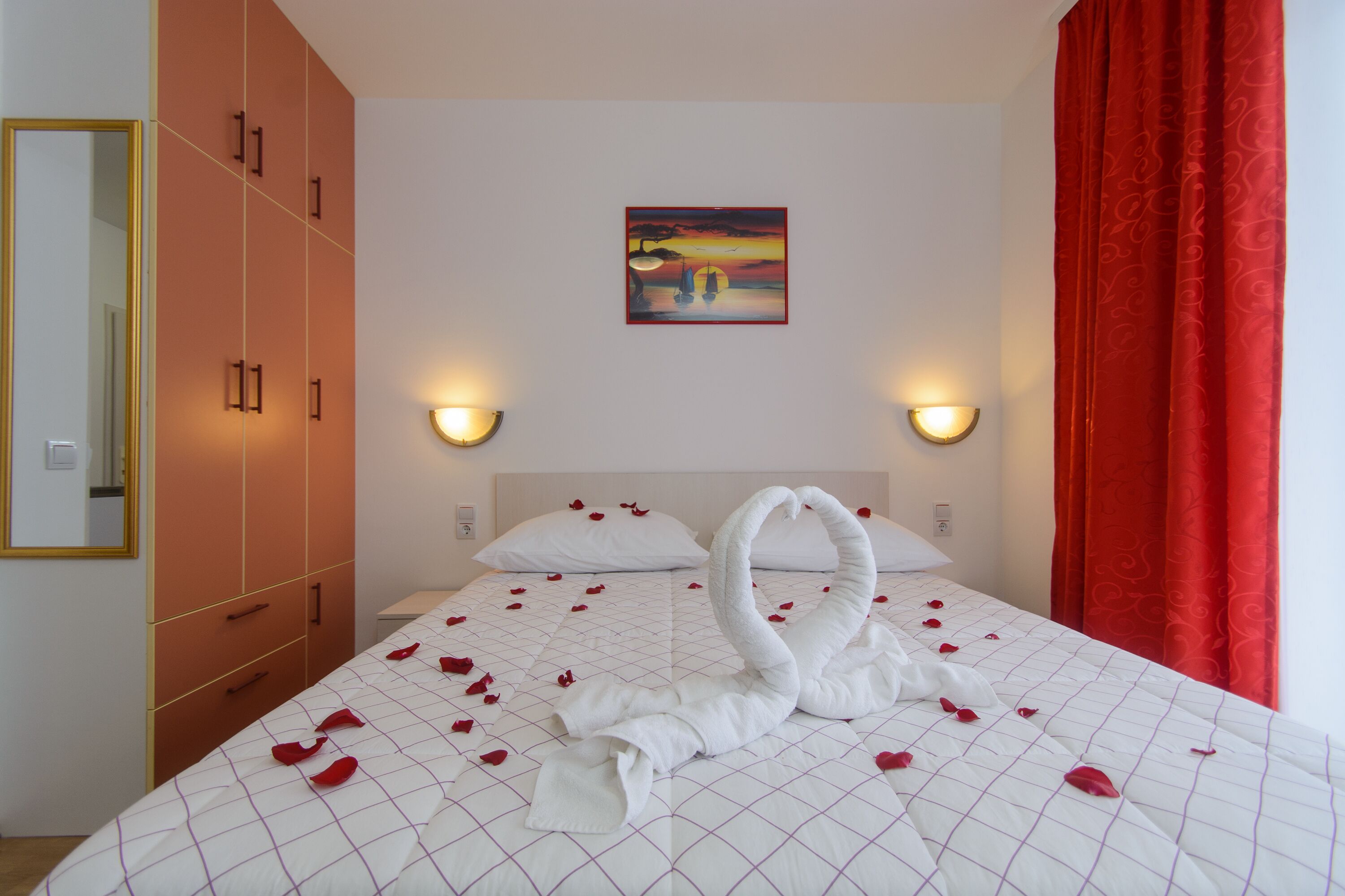 Una habitación de hotel con una cama, un cuadro en la pared y una cortina roja.