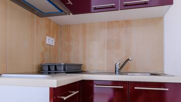 A modern kitchen with dark red cabinets, a stainless steel sink, and a built-in range hood.