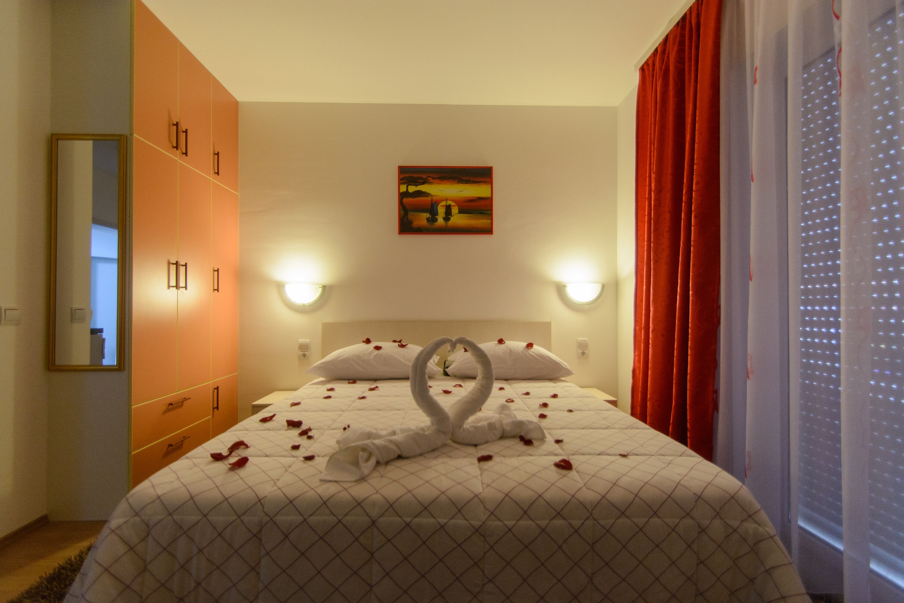 Een hotelkamer met een bed, een schilderij aan de muur en een raam met gordijnen.