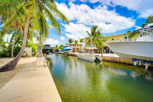 A marina with boats docked, palm trees, and a building with a balcony.