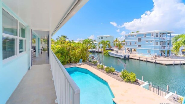 A balcony with a view of a swimming pool, a marina, and nearby buildings.
