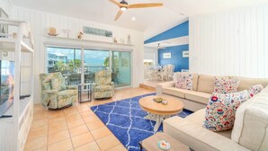 A spacious living area with a large window, a ceiling fan, and a sofa with patterned cushions.