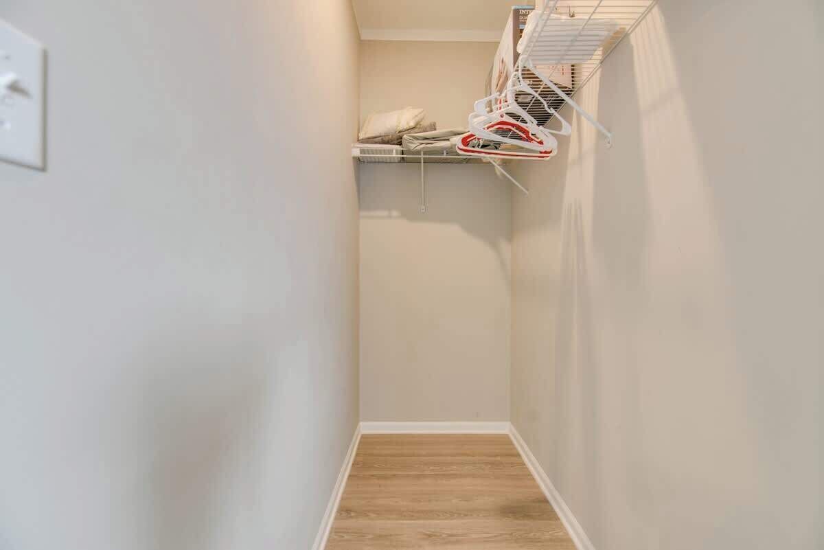 Un pasillo estrecho con suelo de madera y pared blanca.