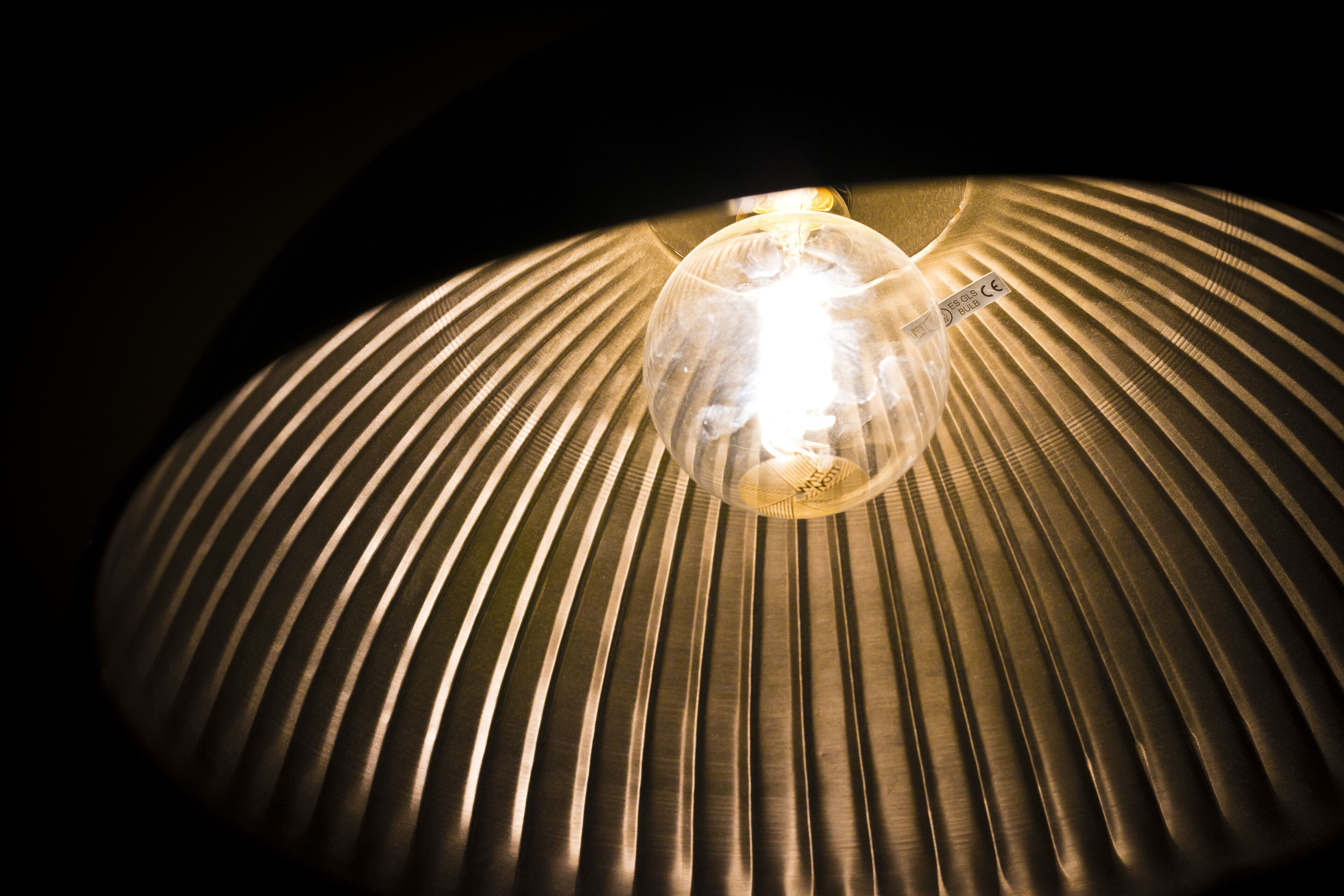A lamp with a ribbed shade and a visible light bulb.