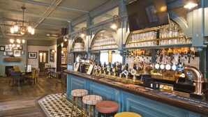 A bar area with stools, a bar counter, and a variety of bottles and glasses. - Bowling Green (Manchester)