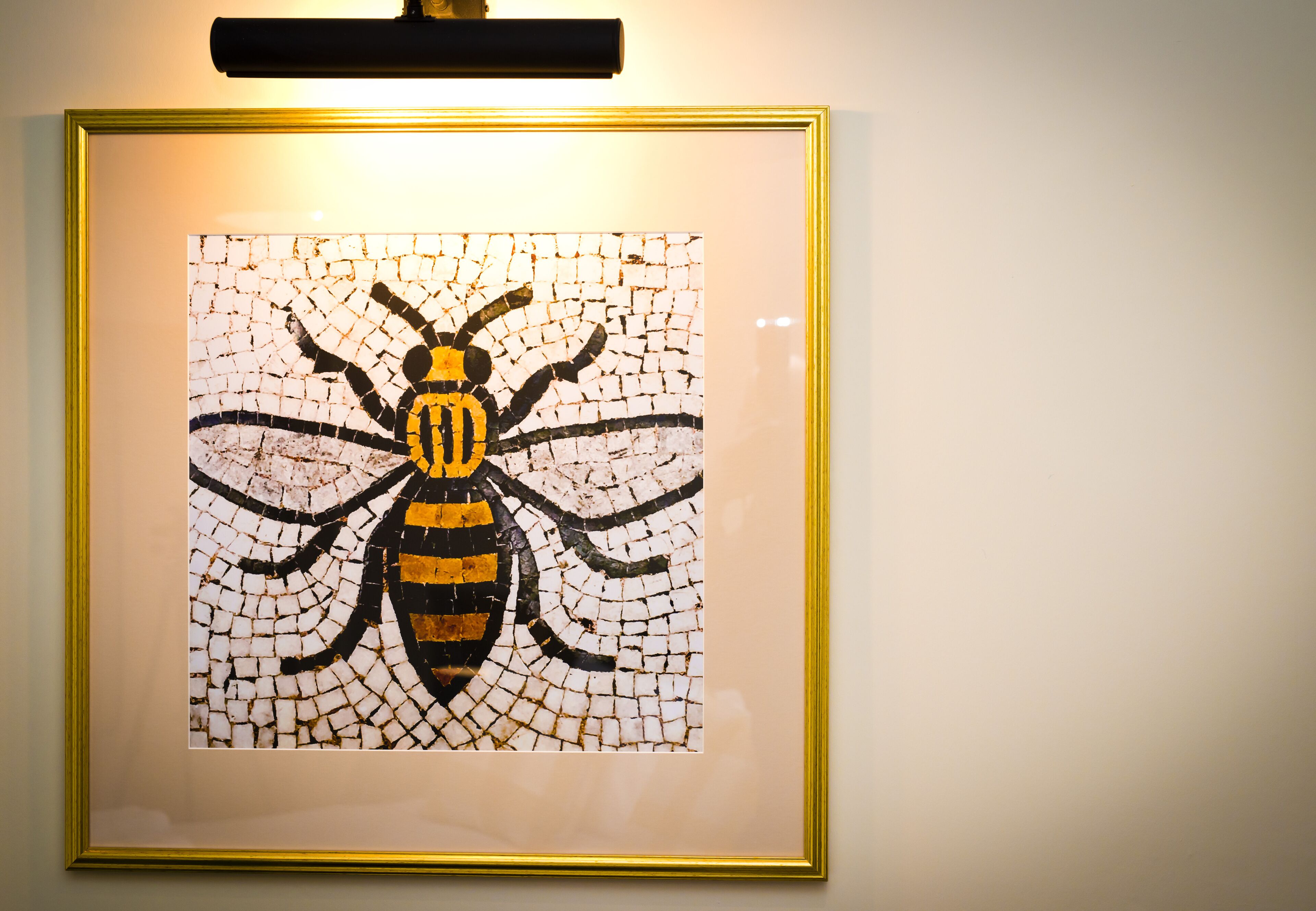 A framed mosaic of a bee on a wall.