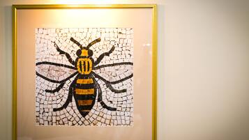 Mosaico enmarcado con la imagen de una abeja en una pared.