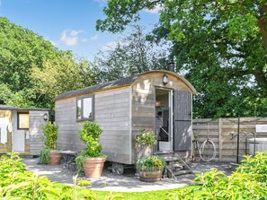 A small wooden cabin with a door open, surrounded by potted plants and a wooden fence. - 1 bedroom accommodation in Strensall, near York (Strensall, near York)
