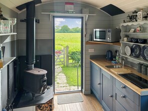 A compact kitchen with a wood stove, a microwave, and a sink. - 1 bedroom accommodation in Strensall, near York (Strensall, near York)