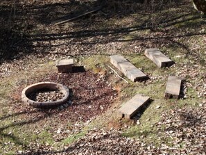 Surrounded by nature, this serene setting features a circular fire pit amidst a grassy area.