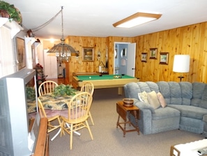 Relax and unwind in this inviting living room, featuring a pool table, comfortable seating, and a television.