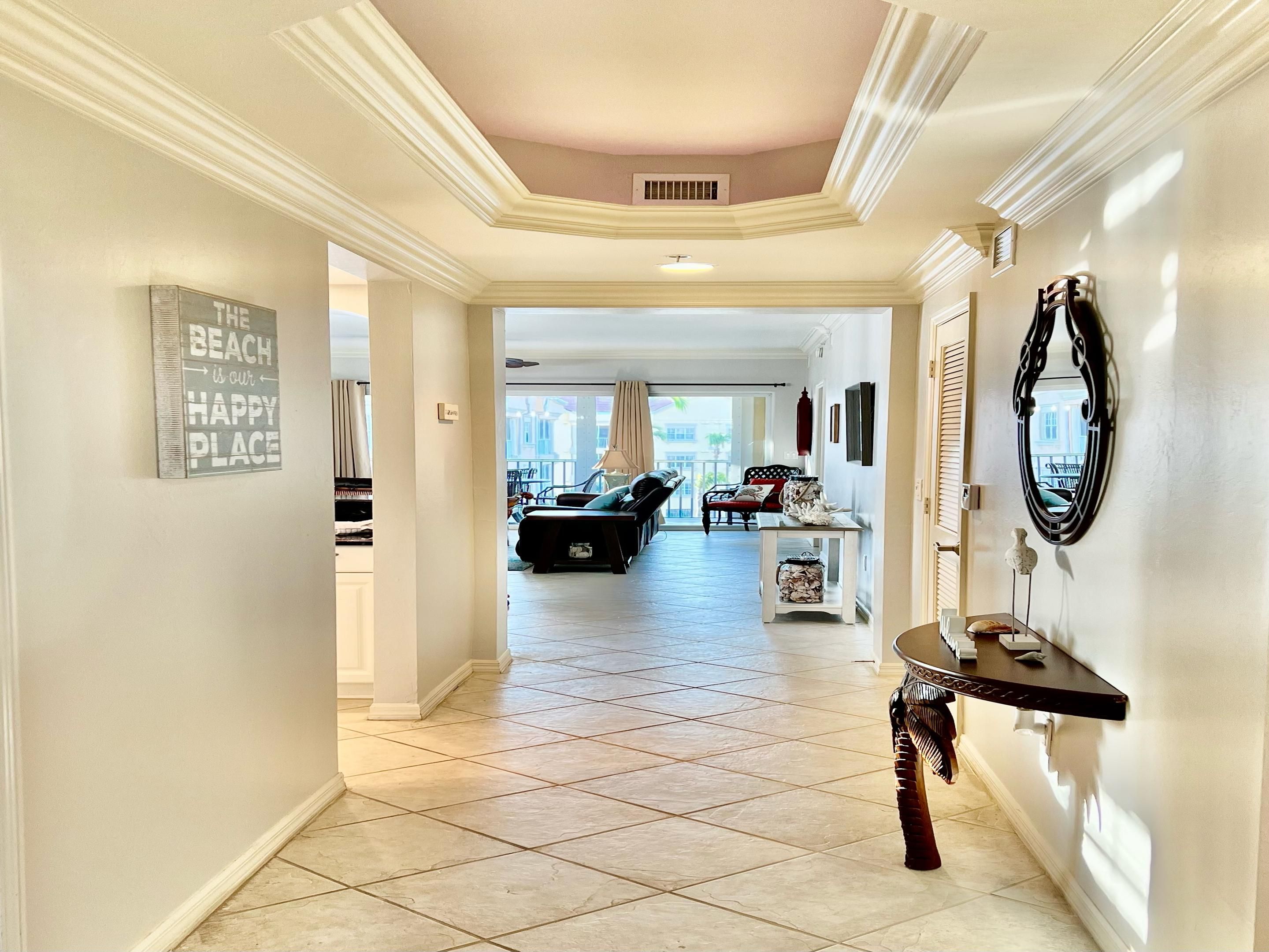 A spacious hallway with a tiled floor, a coat rack, a decorative mirror, and a sign on the wall.