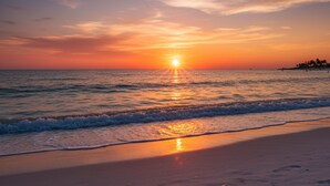 A beach with the sun setting over the ocean, creating a calm and serene atmosphere. - Bella Lago 241 by Distinctive Beach Rentals (Fort Myers Beach)