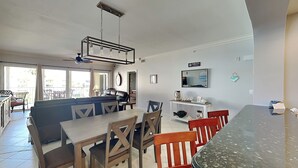 Una sala de estar moderna con comedor, sofá, televisor y ventilador de techo.