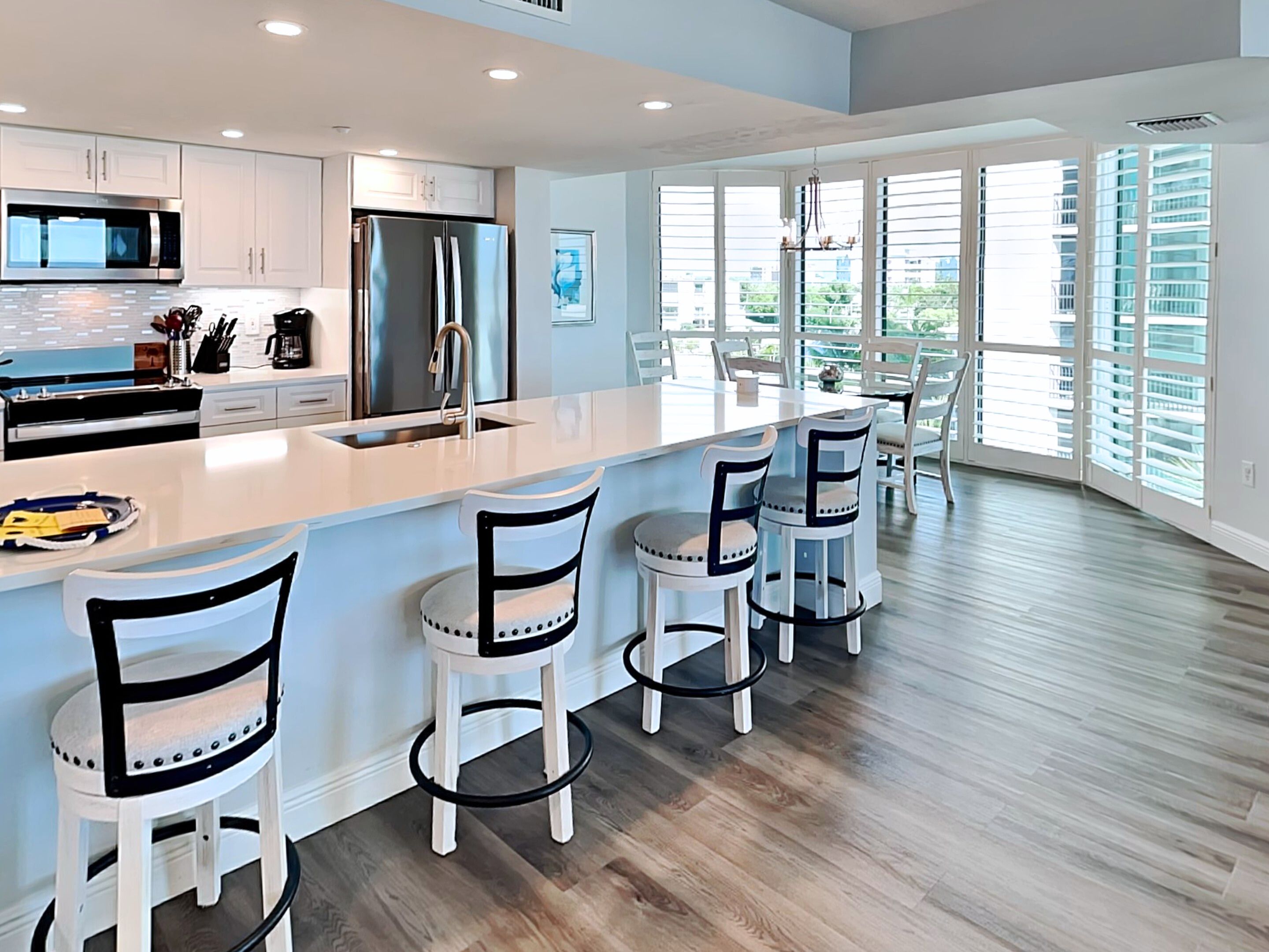 A modern kitchen with white cabinetry, stainless steel appliances, and a large island with bar stools.