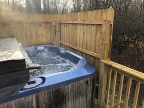A hot tub with a wooden deck and a wooden fence in the background.