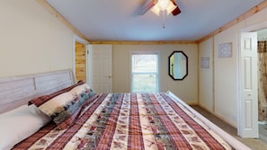 Un dormitorio con una cama grande, ventilador de techo, una ventana y una puerta.