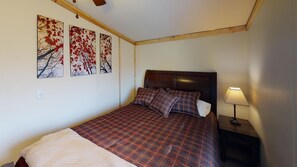 A bedroom with a bed, a nightstand, a lamp, and three wall-mounted paintings.