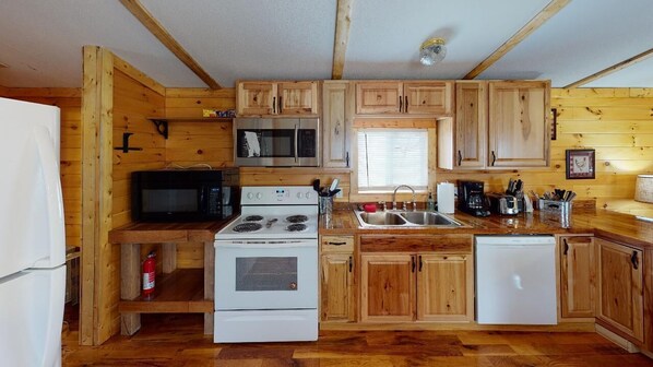 A compact kitchen with wooden cabinets, a microwave, stove, sink, and dishwasher.