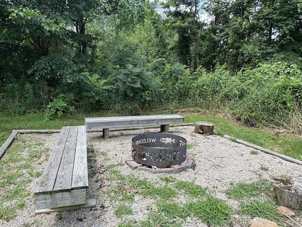 Zona de picnic con banco de madera y fogón.