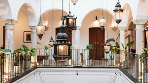 Un interior espacioso con faroles colgantes, columnas blancas y plantas en macetas.