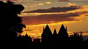 Silhouet van een gebouw met meerdere puntige daken voor een ondergaande zon.