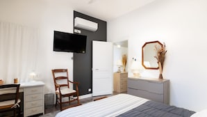 A modern bedroom with a bed, a desk, a chair, a dresser, a mirror, and an air conditioning unit. - House Châteaudun - Air conditioning, Terrace & Private garage (Carcassonne)