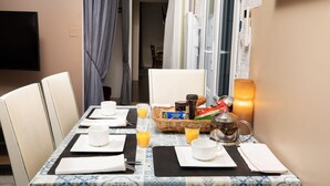 A dining table set with white plates, cups, and cutlery, accompanied by a basket of bread and a teapot. - House Châteaudun - Air conditioning, Terrace & Private garage (Carcassonne)