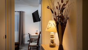 A room with a wooden desk, a chair, a lamp, and a wall-mounted TV. - House Châteaudun - Air conditioning, Terrace & Private garage (Carcassonne)
