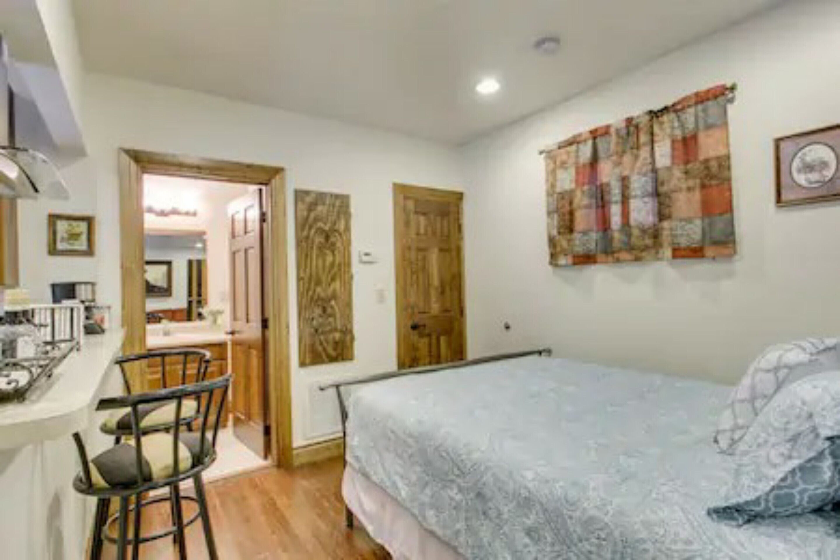 A bedroom with a bed, a desk with chairs, and a door leading to a bathroom.