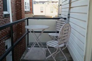 A small balcony with a metal table and two chairs. - Evie's apartment (Oklahoma City)