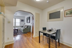 A dining area with a wooden table and chairs, a sofa in the background, and a door leading to another room. - Evie's apartment (Oklahoma City)