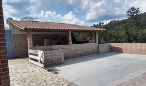 Zona de pati exterior amb mur de maó, teulada ceràmica i sòl de pedra.
