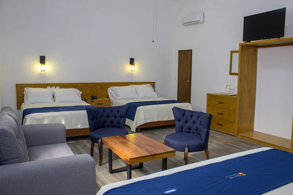 Habitación de hotel con dos camas, un sofá, una mesa y una televisión.