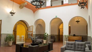 Un vestíbulo amplio con una mesa de recepción, zona de estar y varios arcos.