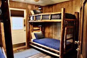 A bunk bed room with wooden walls and a door.