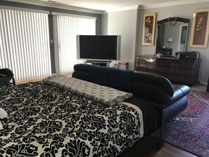 Quarto de hotel com uma cama grande, televisão, cômoda e espelho.