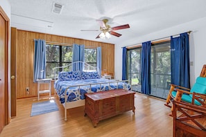A bedroom with a bed, a wooden chest, a chair, and a ceiling fan. - Charming 2 bedroom house in the heart of Downtown Wimberley! Walk to the Square! (Wimberley)