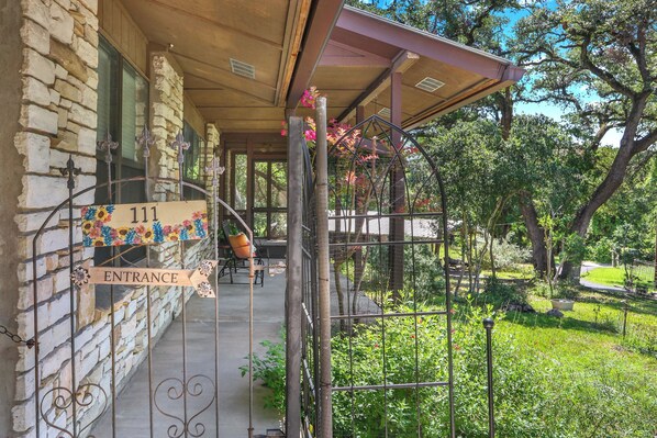 A stone building with a wooden porch, a metal gate, and a sign reading 'Entrance'.