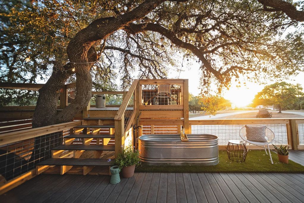 A wooden deck with a hot tub, a chair, and a small table.