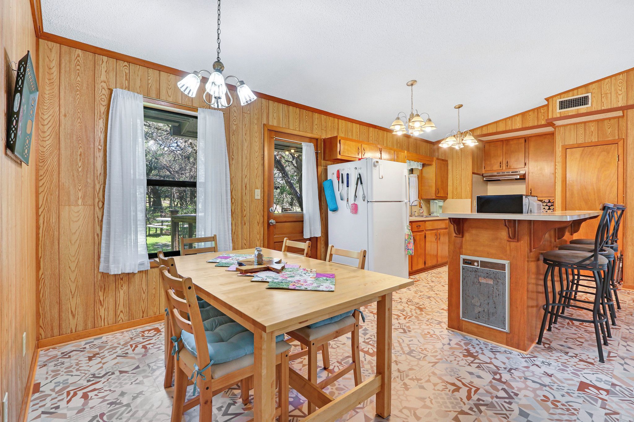 A wooden-paneled kitchen with a dining table, chairs, and a bar area.