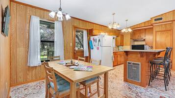 A wooden-paneled kitchen with a dining table, chairs, and a bar area.
