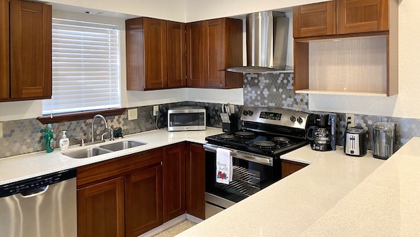 A kitchen with wooden cabinets, a stainless steel range hood, a microwave, a stove, and a toaster. - Garage Studio near OUSHC Hospital (Oklahoma City)
