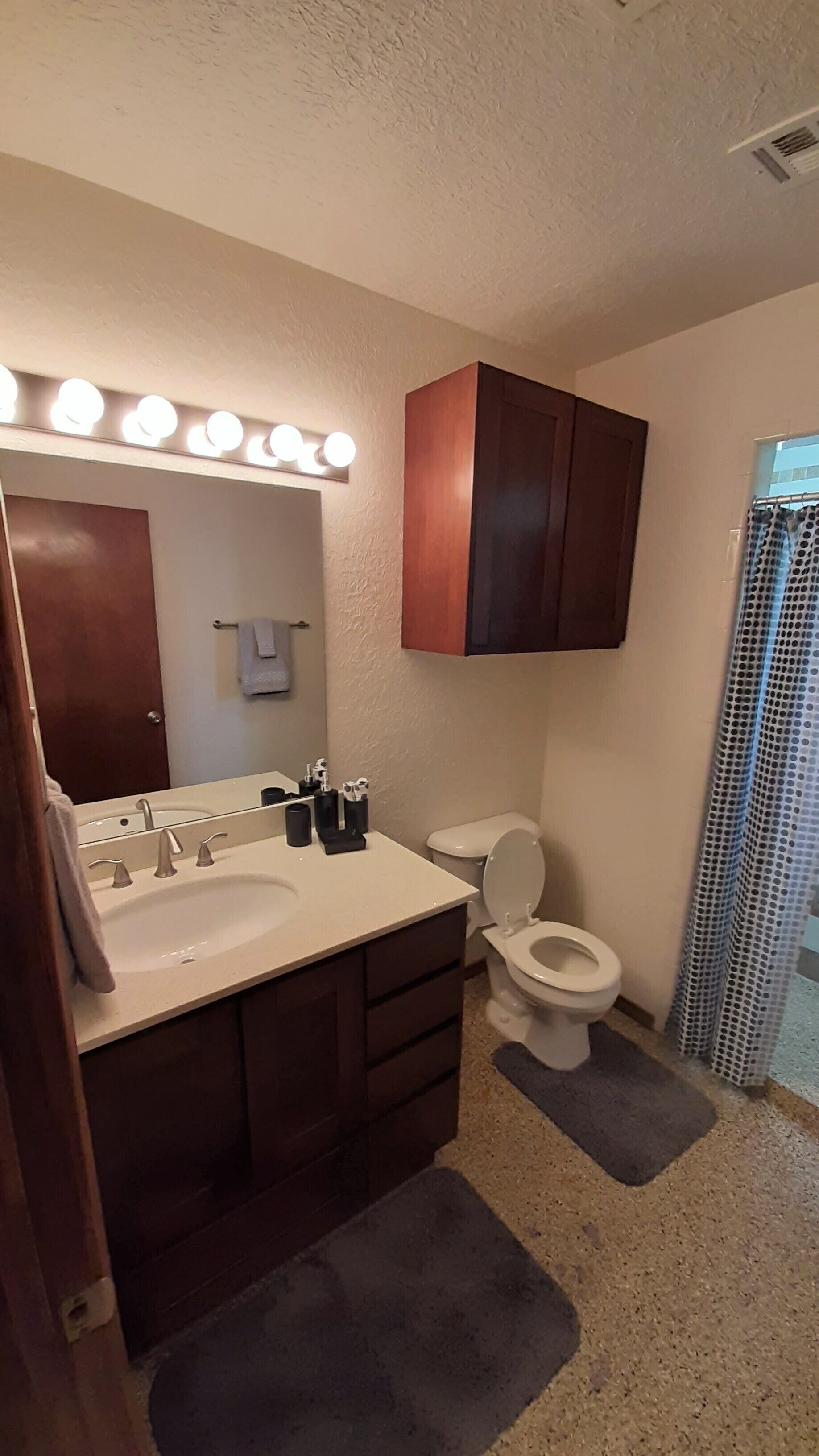 Ein Badezimmer mit Waschtisch, Spüle, Spiegel und Toilette.
